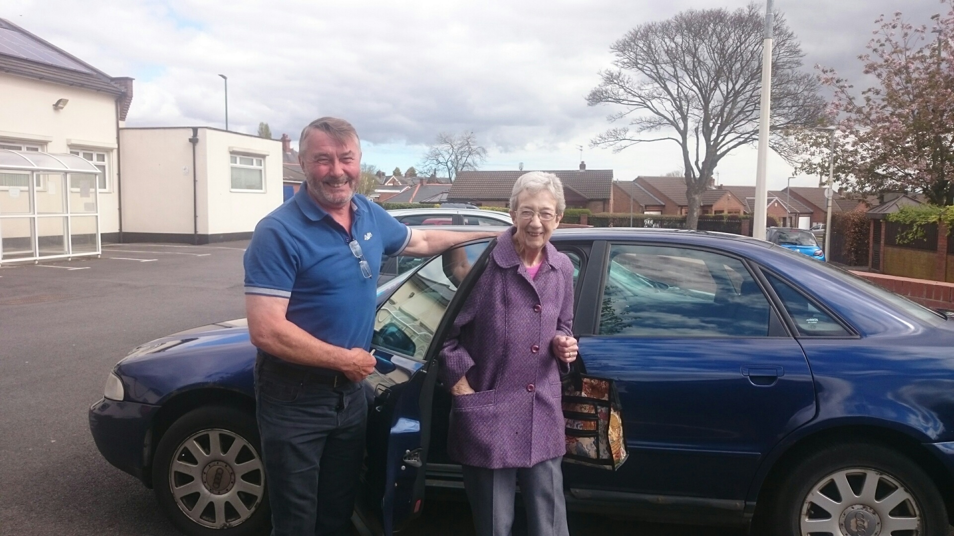 John, volunteer driver with one of his passengers, Gwen next to a car