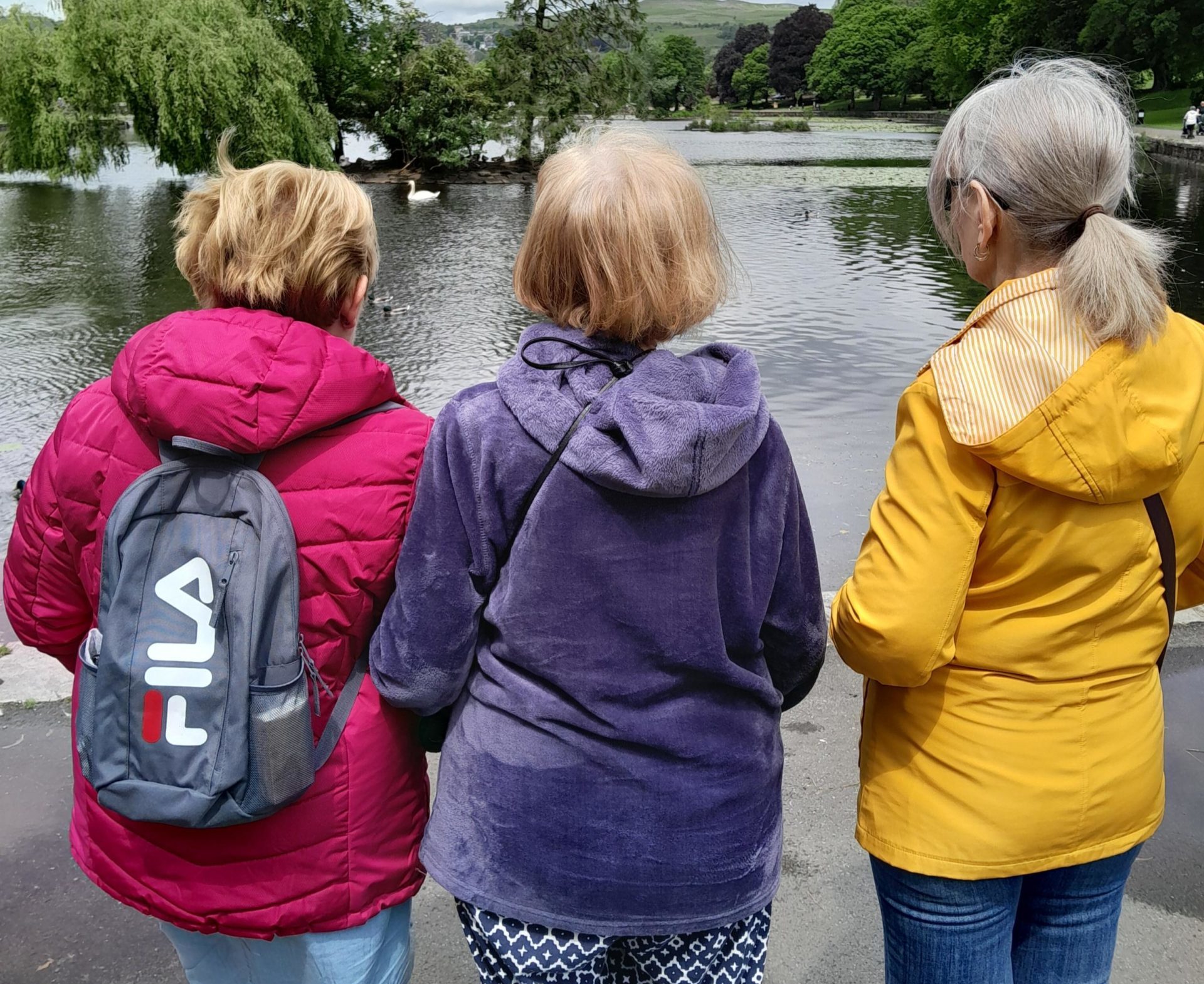 Three people looking out to a pond with the photo being taken from the back