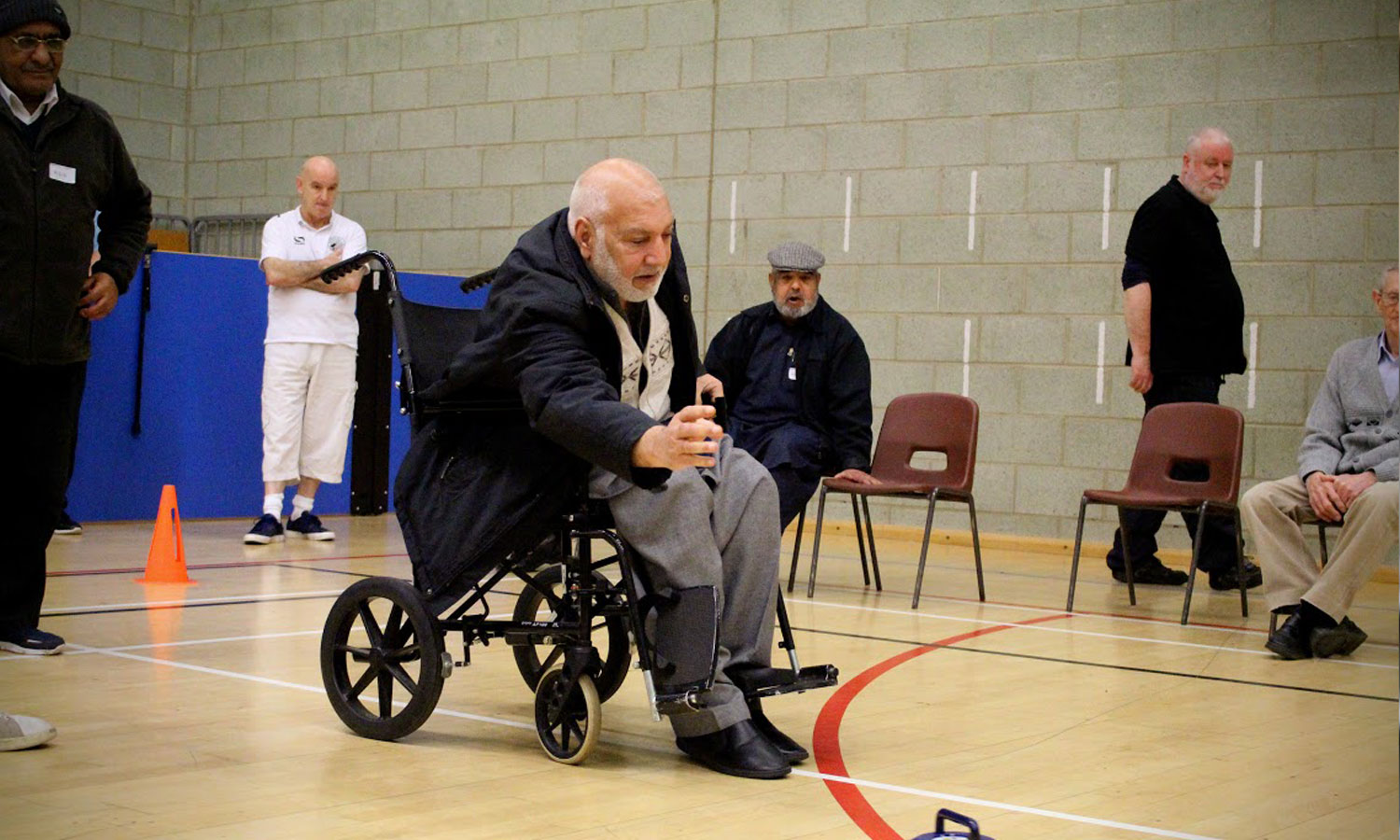 A man on a wheelchair indoors bowling