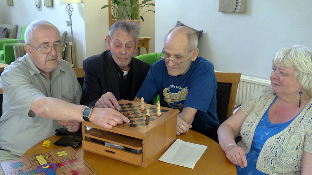 Four people sat at a table playing chess