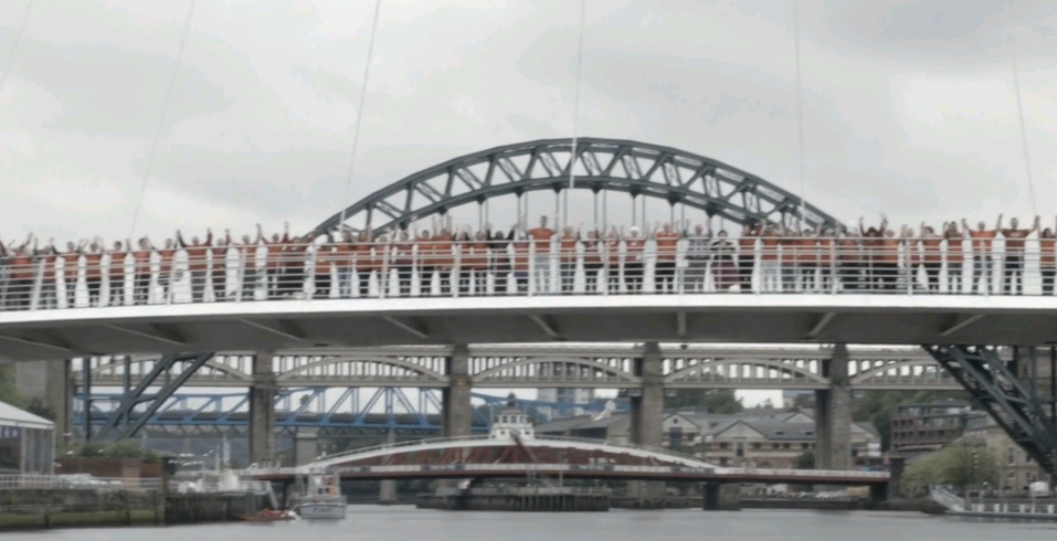 Image of volunteers in Newcastle stood side by side on a bridge