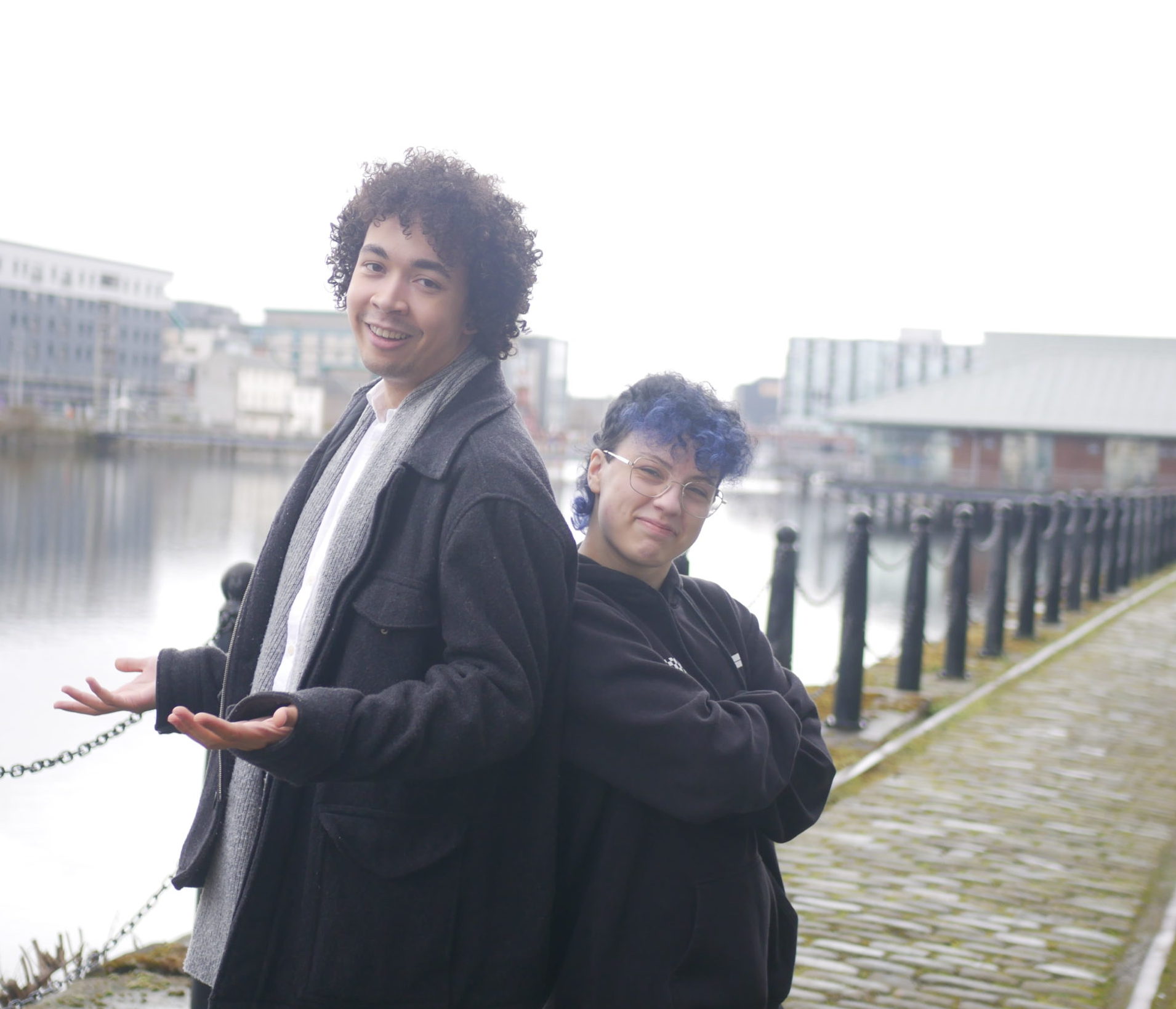 Two young people standing side by side near to water