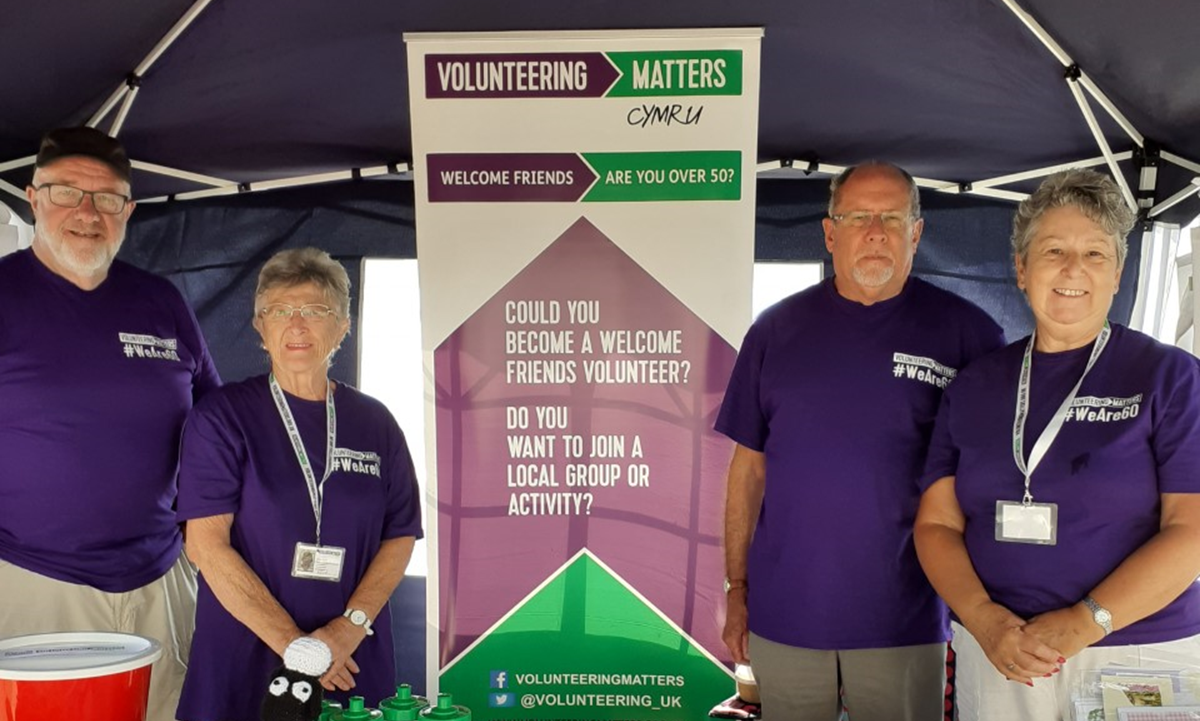 Four volunteers under a tent in front of an RSVP banner
