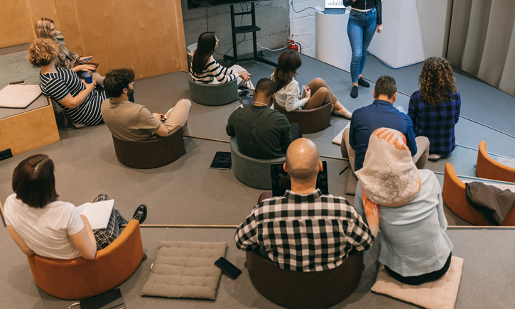 A person presenting to a room with everyones back to the camera