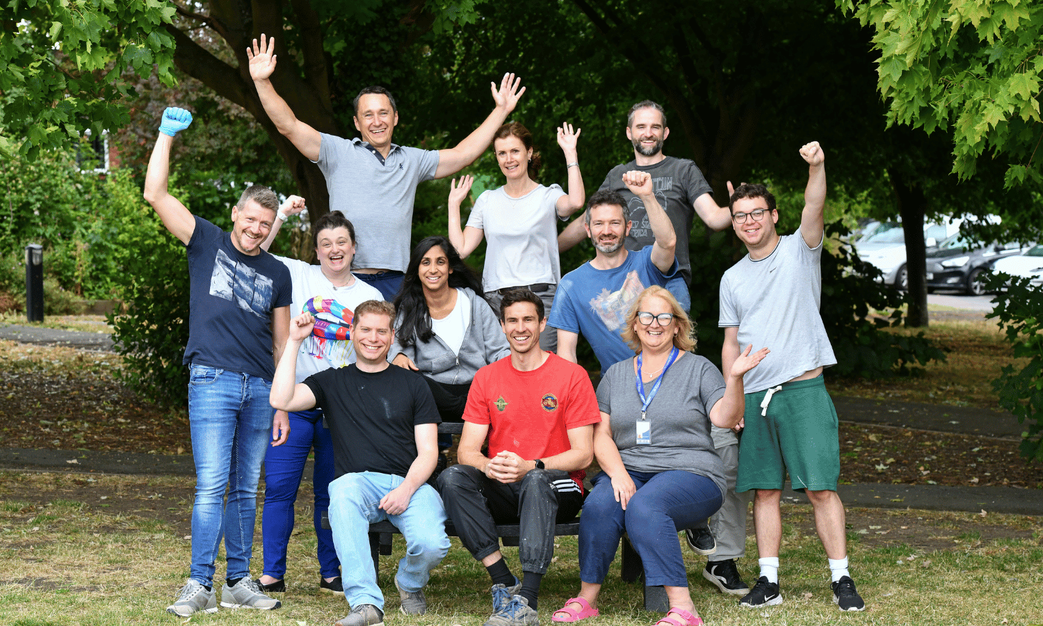 Eleven people posing for a photo with arms raised in the air