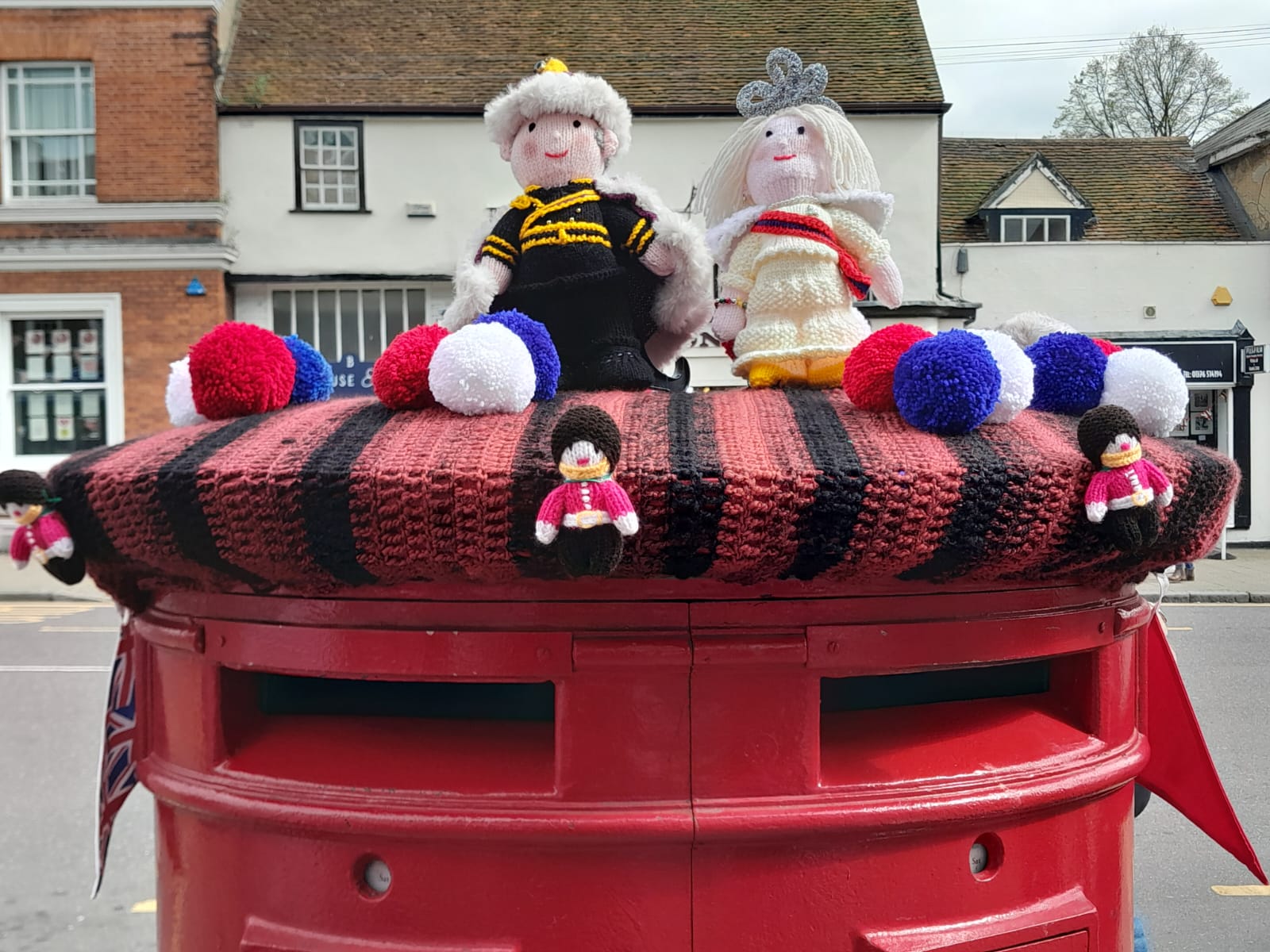 Two knitted characters, a king and queen, on top of a red postbox