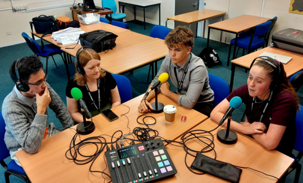 Four people sat around a table speaking into microphones