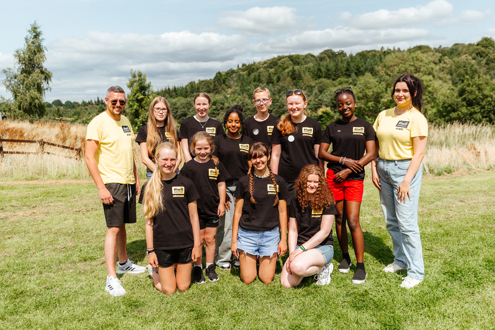 Young people and staff standing outside in a field posing to the camera