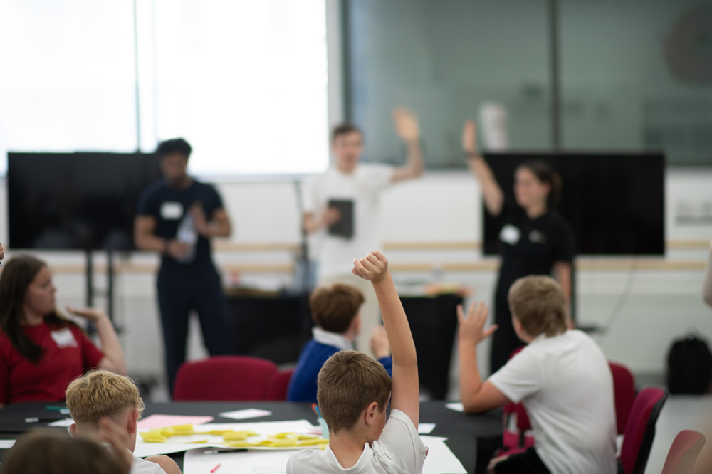 Young people in a room with their hands in the air.