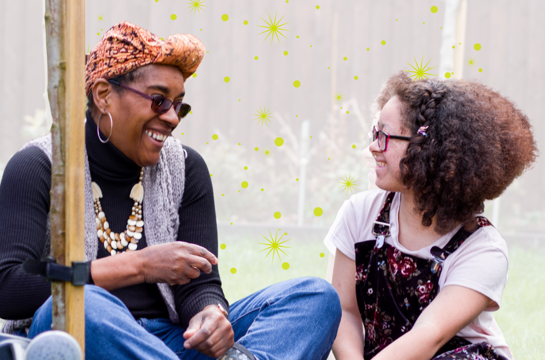 An adult and a young person sitting down on a lawn